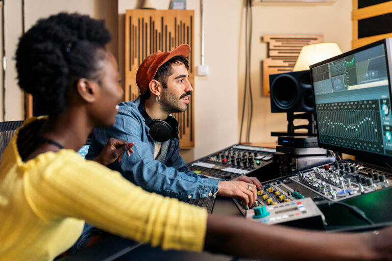photo of happy Black singer working in professional music studio with young music producer