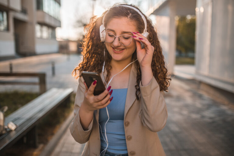 A beautiful young female student listens to music through headphones while walking