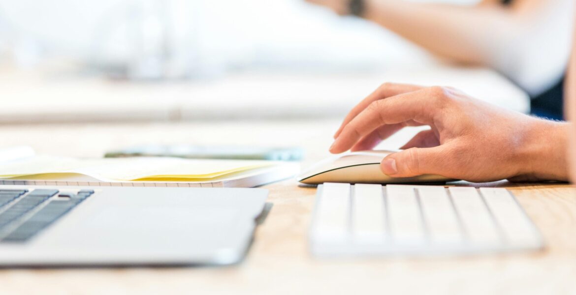 a hand clicking a mouse, with the keyboard showing as well (but cut off)