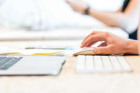 a hand clicking a mouse, with the keyboard showing as well (but cut off)